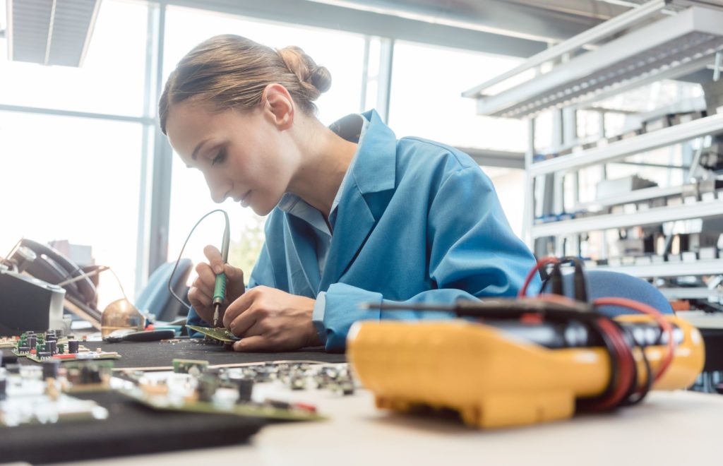 Electronics manufacturing worker soldering a component to complete a PCBA prototyping job