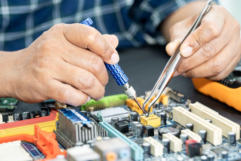 Technician working on printed circuit board assembly (PCBA) with soldering tool.